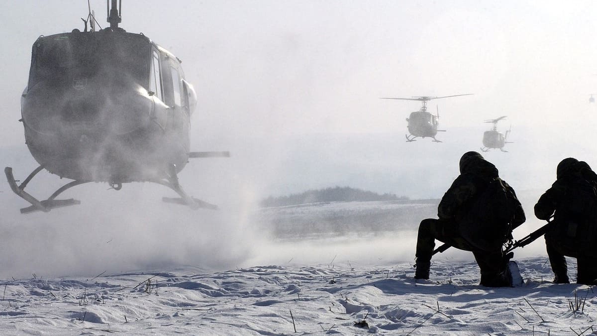 helicopter lands in snow. two people with weapons kneel on the ground. two more helicopters follow close behind.