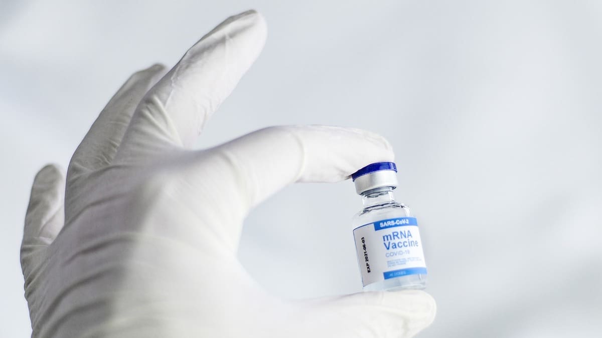 latex-gloved hand holds an mRNA vaccine vial
