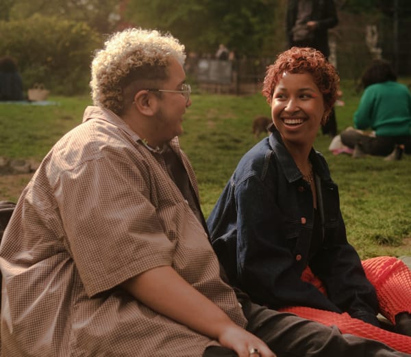 two people seated in a park, having a happy conversation