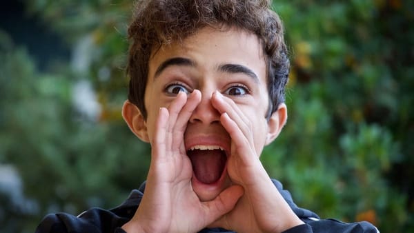 excited teen shouts, cupping hands to mouth to be louder