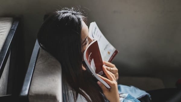 person reading on the train, nose pressed into book