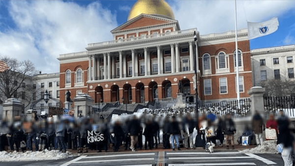 About 20 people lined up in front of the Massachusetts State House. Their faces are blurred.