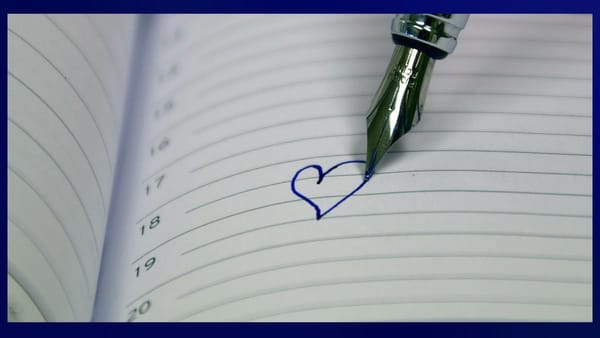 fountain pen drawing a single blue heart on an otherwise empty calendar — the 18th day of the month