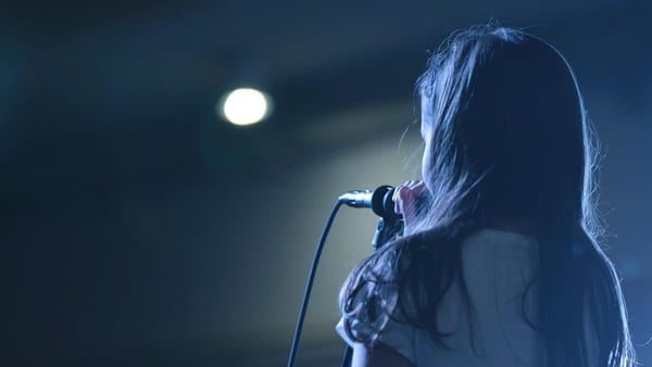 person speaking at a microphone, seen from behind