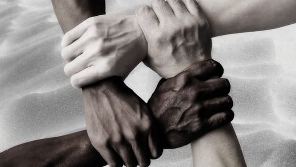 four hands in a circle, holding each other's wrists