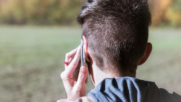 short-haired person talking on mobile phone outdoors