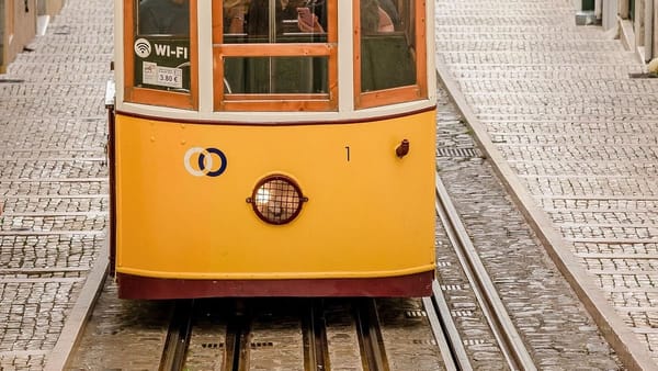 yellow tram car with passengers, flat train tracks, cobblestone street